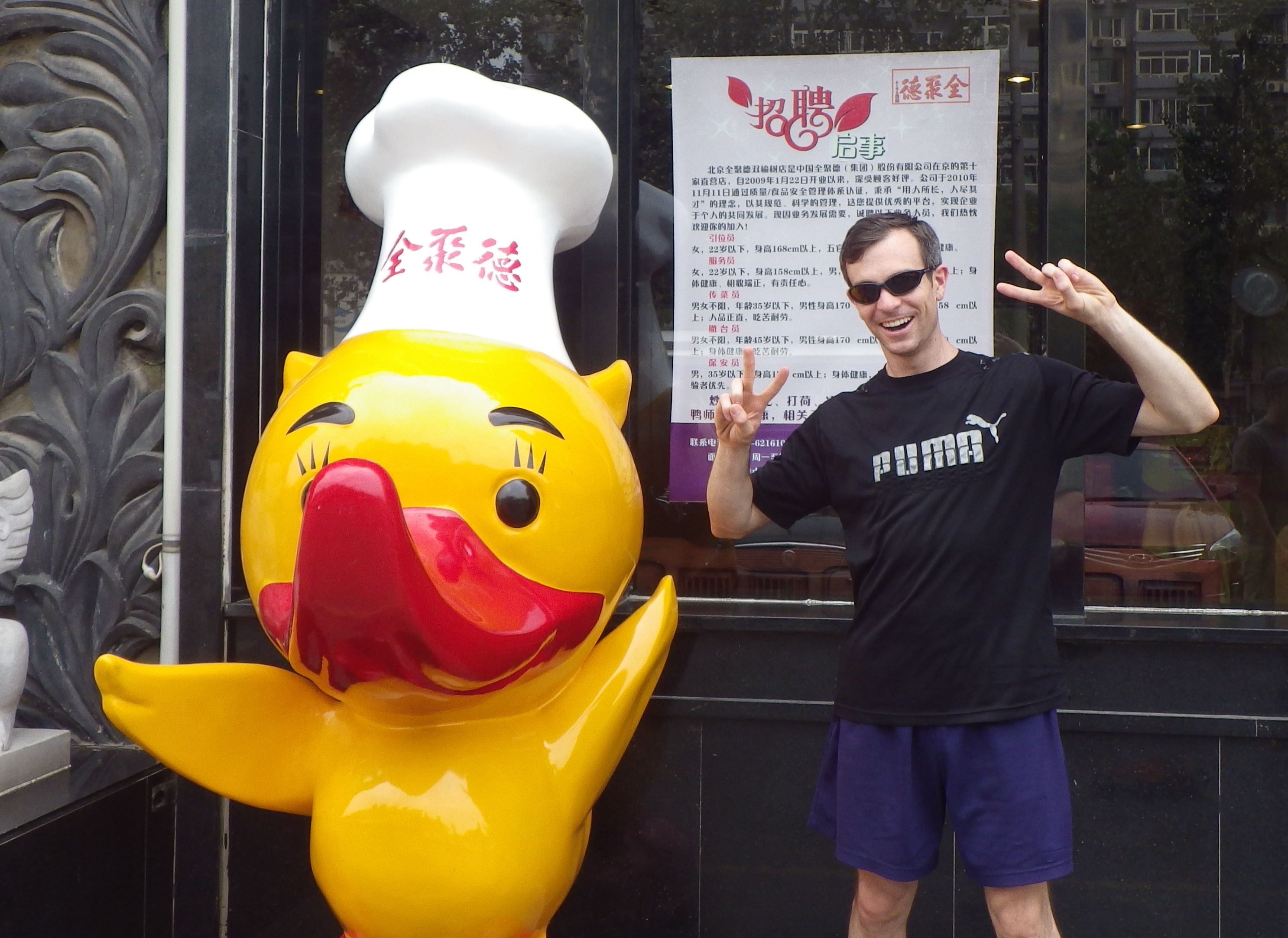 John standing next to a Beijing roast duck mascot in Beijing in 2014